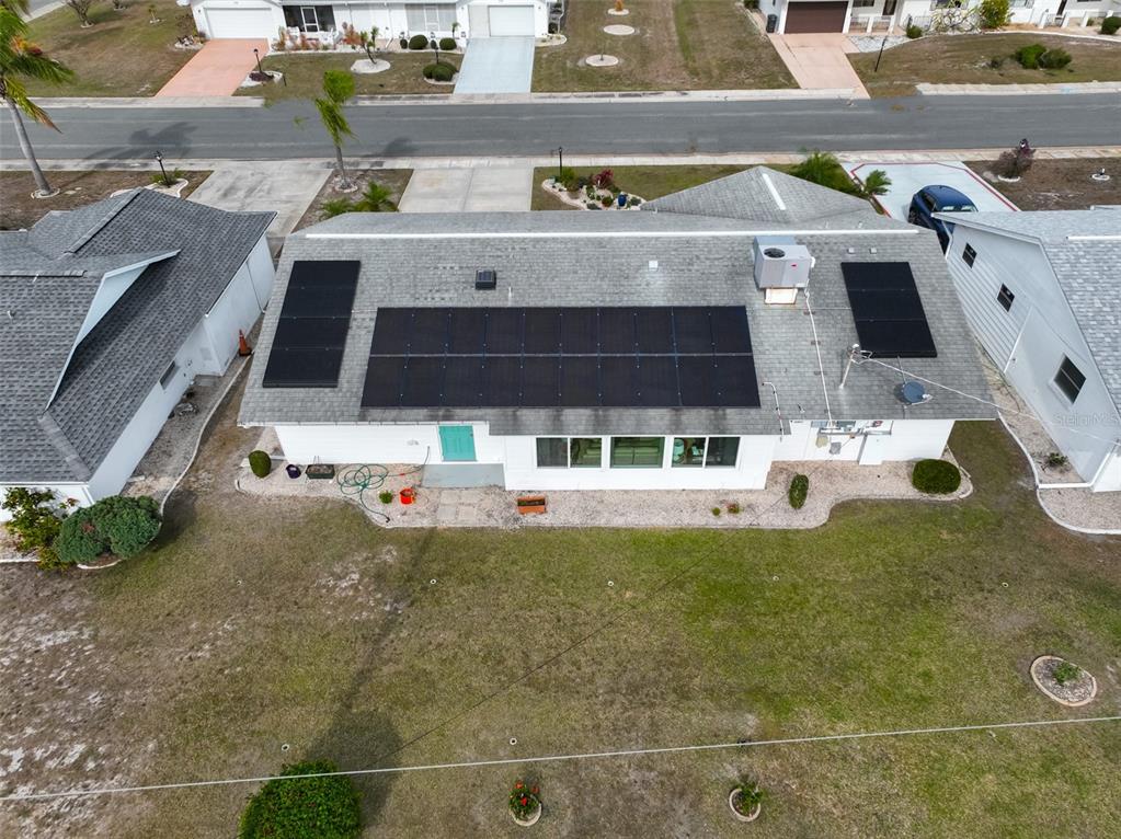 An aerial view shows a house with a shingled roof featuring several solar panels — 1520 DANBURY DRIVE, SUN CITY CENTER, FL