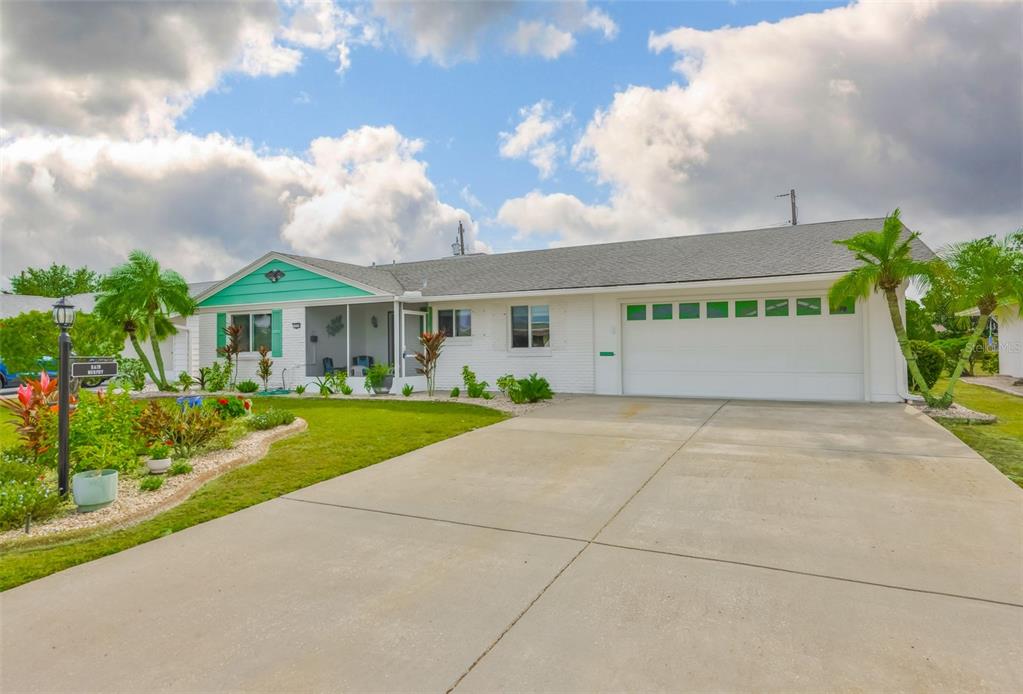 A white single-story house with a teal gable, screened porch, and a two-car garage — 1520 DANBURY DRIVE, SUN CITY CENTER, FL