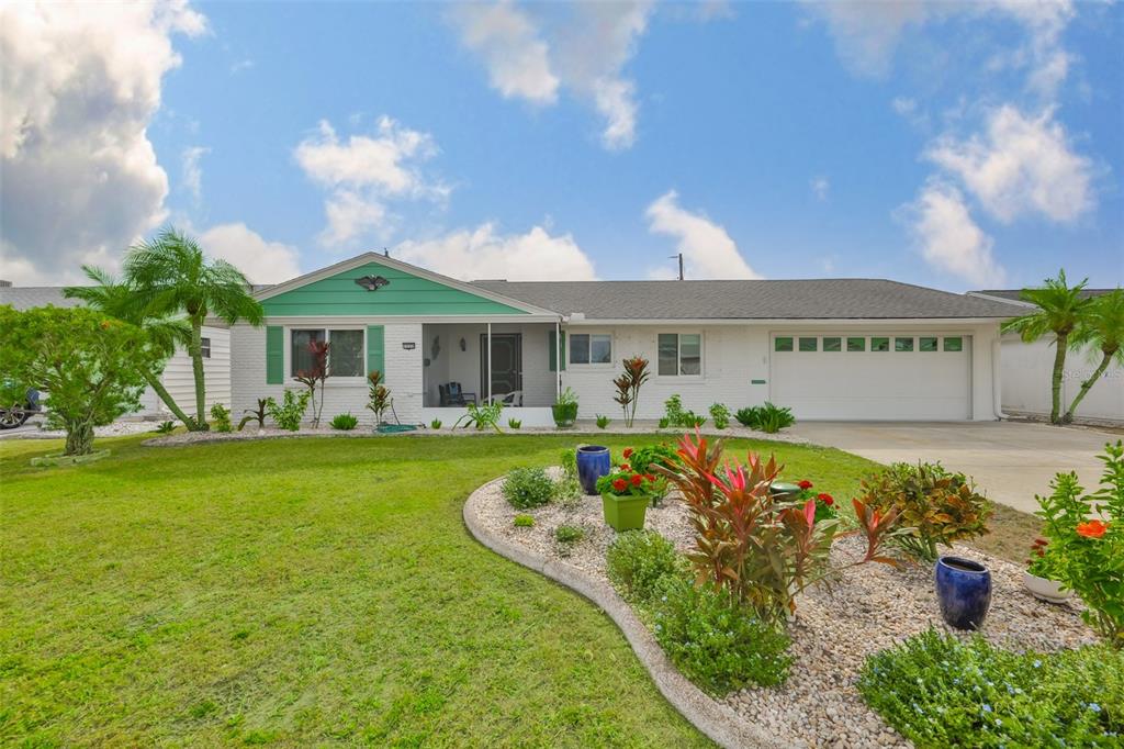 A single-story white house with a green gable and a front lawn with landscaping — 1520 DANBURY DRIVE, SUN CITY CENTER, FL