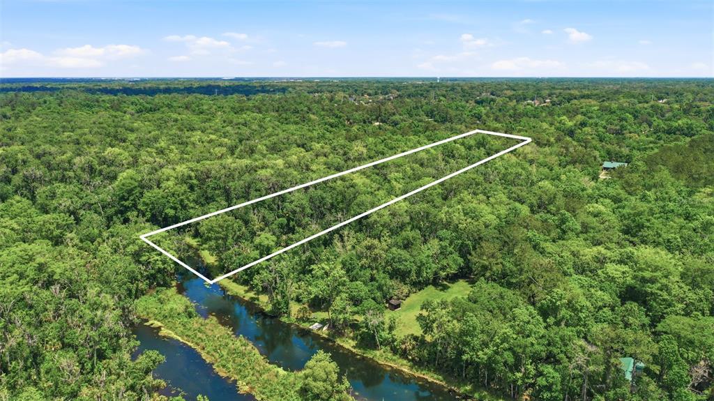 An aerial view shows a rectangular plot of land outlined in white amidst dense forest — DELK ROAD, LONGWOOD, FL