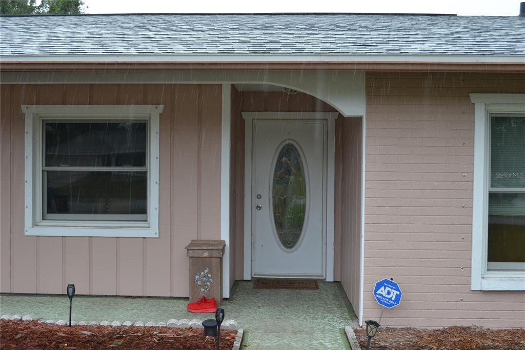 The exterior of a house features a white front door, brick siding, and a walkway — 6496 TOLEDO ROAD, SPRING HILL, FL