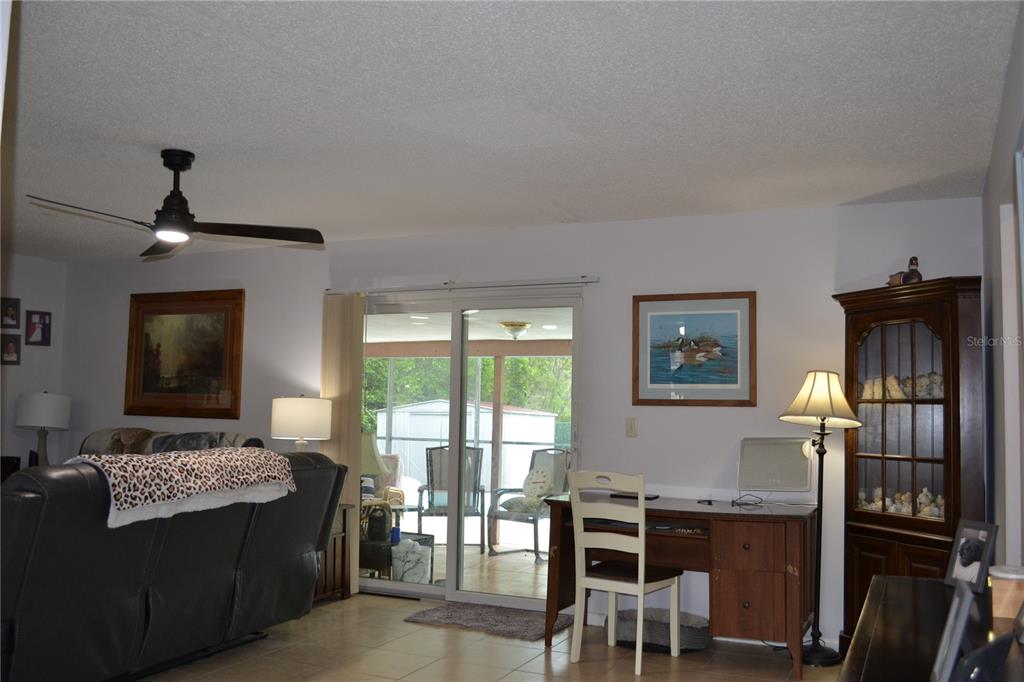A living room with a desk, sliding glass doors, and a view of a patio — 6496 TOLEDO ROAD, SPRING HILL, FL