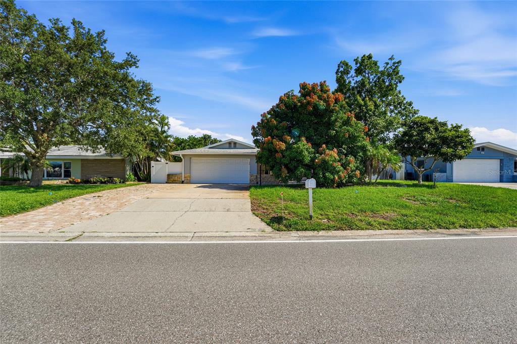 A single-story house with a brick driveway, a two-car garage, and mature landscaping — 14233 102ND AVENUE, LARGO, FL
