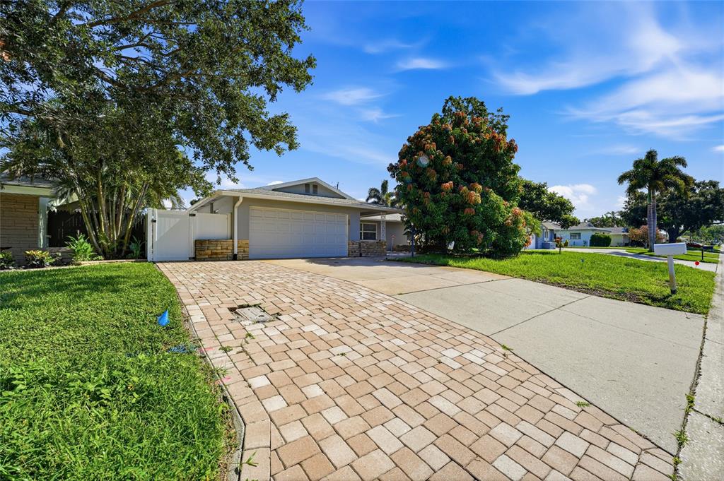 A single-story house features a two-car garage, stone accents, and a paved driveway — 14233 102ND AVENUE, LARGO, FL