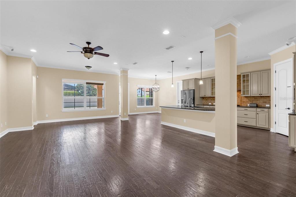 An open-concept living and kitchen area features dark hardwood floors, beige walls, and a large island — 7231 SANGALLA DRIVE, WINDERMERE, FL