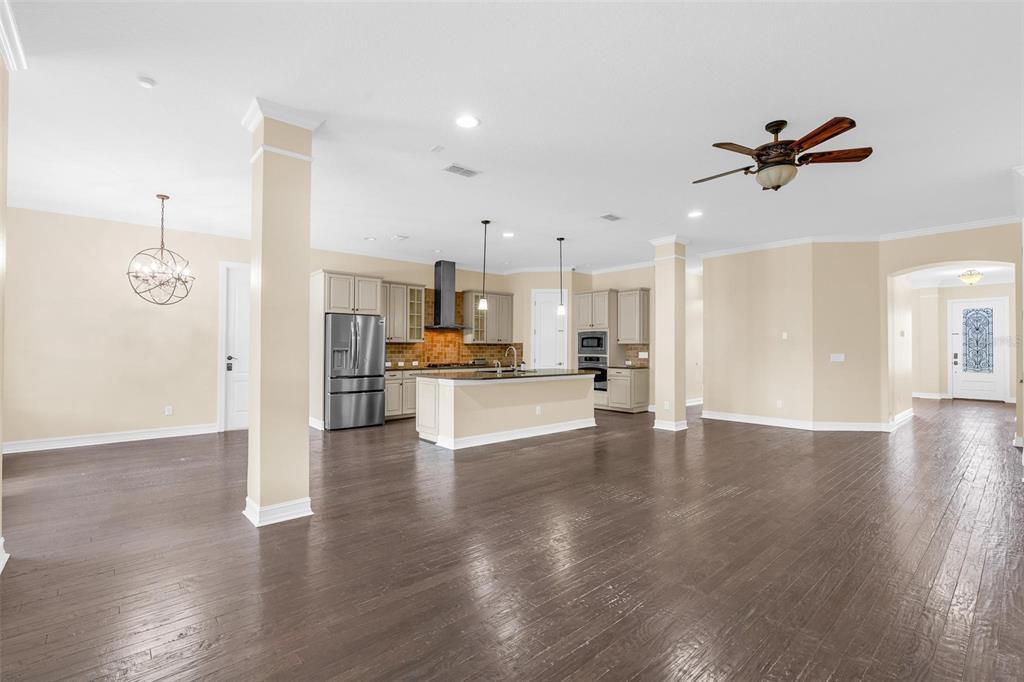 An open-concept kitchen with a central island, stainless steel appliances, and dark hardwood flooring — 7231 SANGALLA DRIVE, WINDERMERE, FL