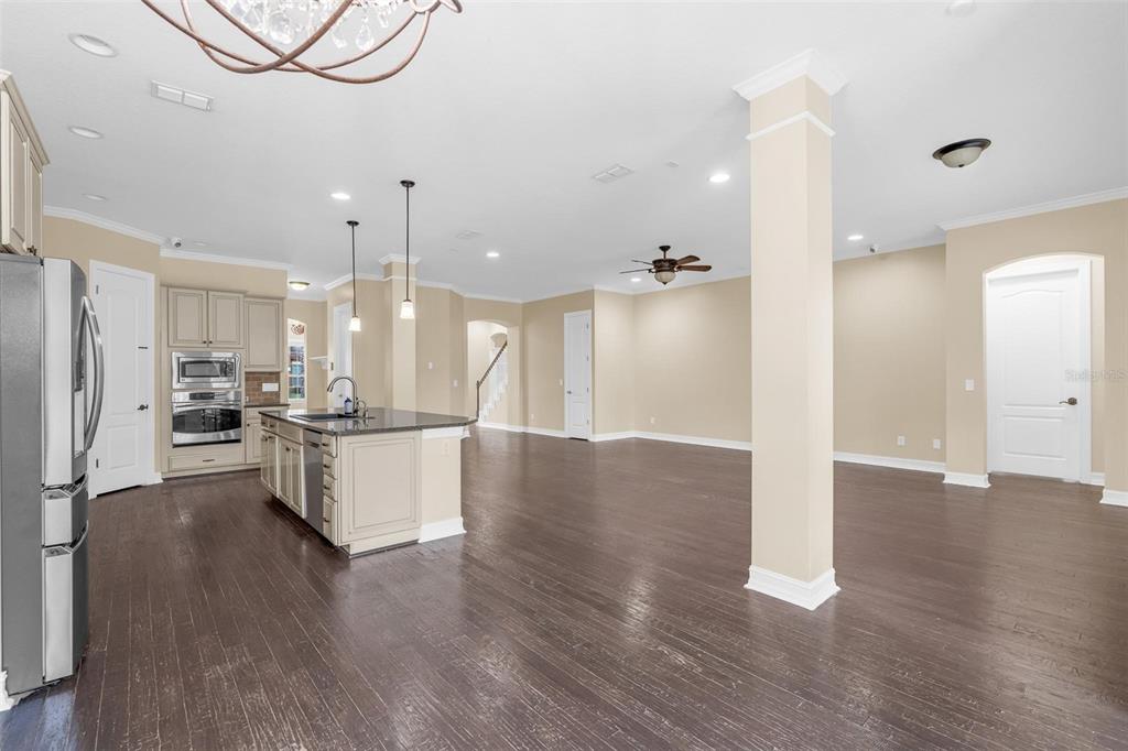 A kitchen with a center island and dark wood floors opens into a spacious living area — 7231 SANGALLA DRIVE, WINDERMERE, FL