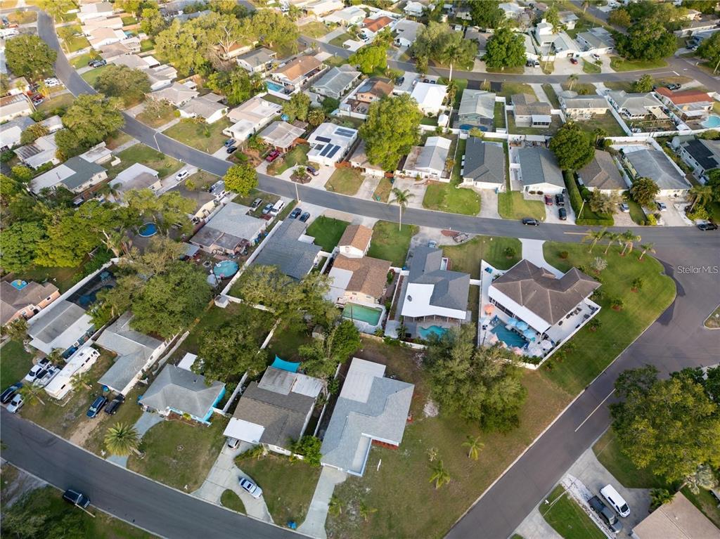 An aerial view shows a residential neighborhood with houses, swimming pools, and paved streets — 10341 KUMQUAT LANE, SEMINOLE, FL