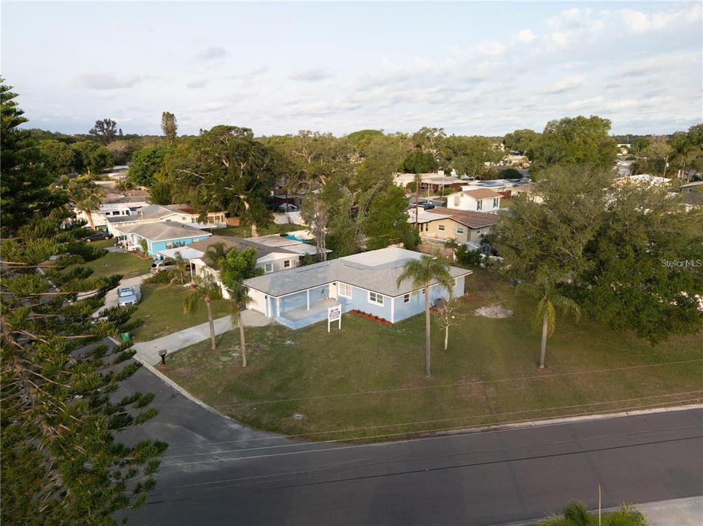 An aerial view shows a light blue house with a gray roof and palm trees — 10341 KUMQUAT LANE, SEMINOLE, FL