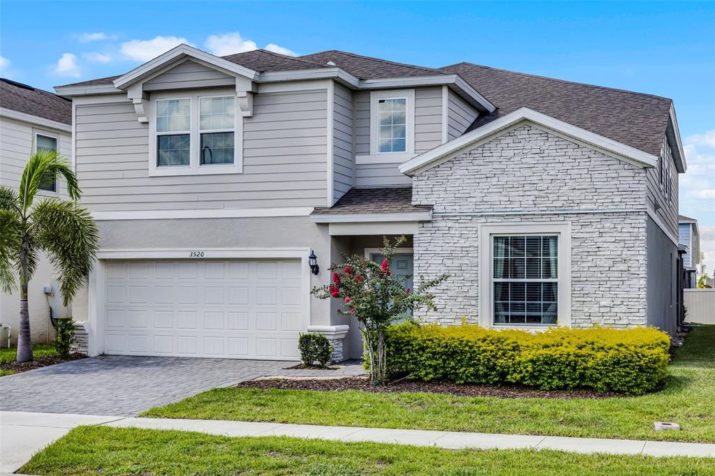 A two-story house features gray horizontal siding, a stone facade, and a two-car garage — 3520 LAVENDER DRIVE, DAVENPORT, FL