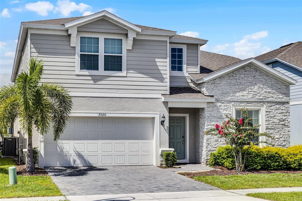 A two-story house with gray siding, a stone facade, and a paved driveway — 3520 LAVENDER DRIVE, DAVENPORT, FL