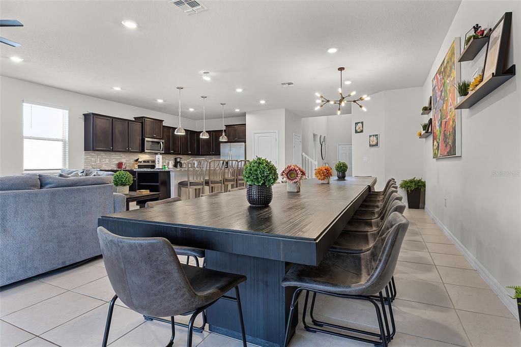 A dining room with a long dark table and chairs sits adjacent to an open kitchen — 3520 LAVENDER DRIVE, DAVENPORT, FL