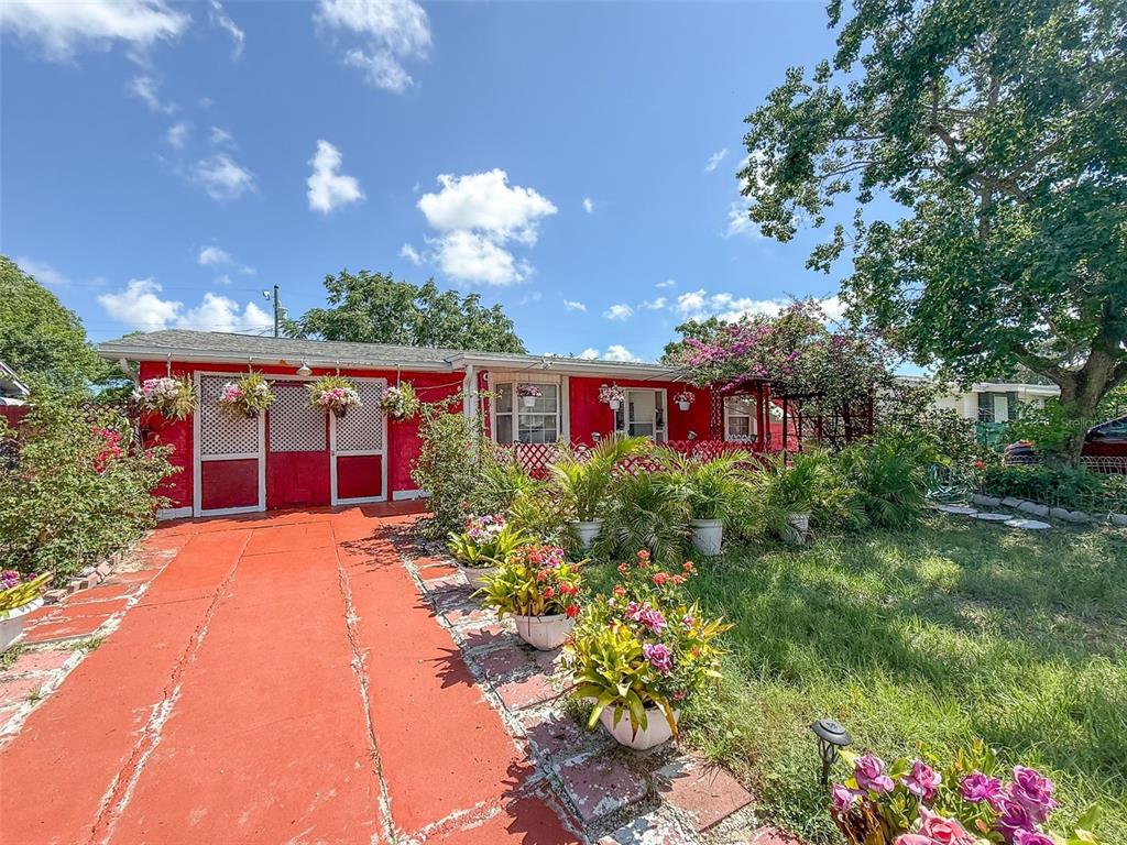 A red house with a matching driveway, potted plants, and a large tree in the yard — 4737 LONGWOOD AVENUE, HOLIDAY, FL