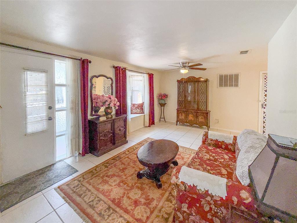 A living room features tile flooring, a floral sofa, a wooden coffee table, and furniture — 4737 LONGWOOD AVENUE, HOLIDAY, FL