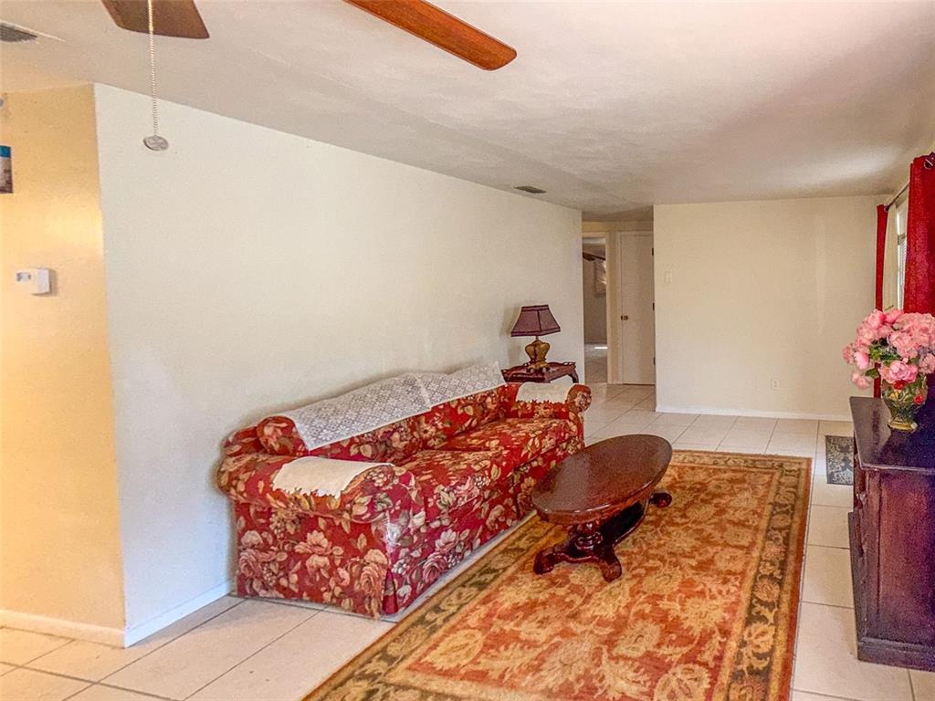 A living room features a floral sofa, an oval coffee table, and a patterned rug — 4737 LONGWOOD AVENUE, HOLIDAY, FL