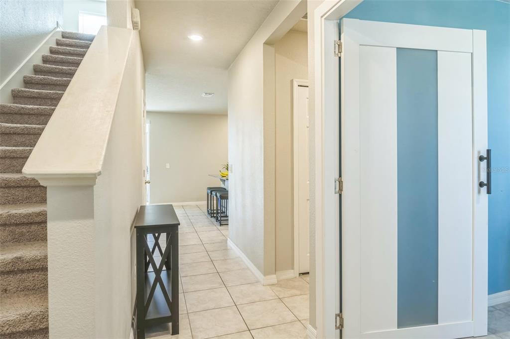 A hallway features carpeted stairs, a console table, tile flooring, and a modern interior door — 1262 CITRUS LANDINGS BOULEVARD, DAVENPORT, FL