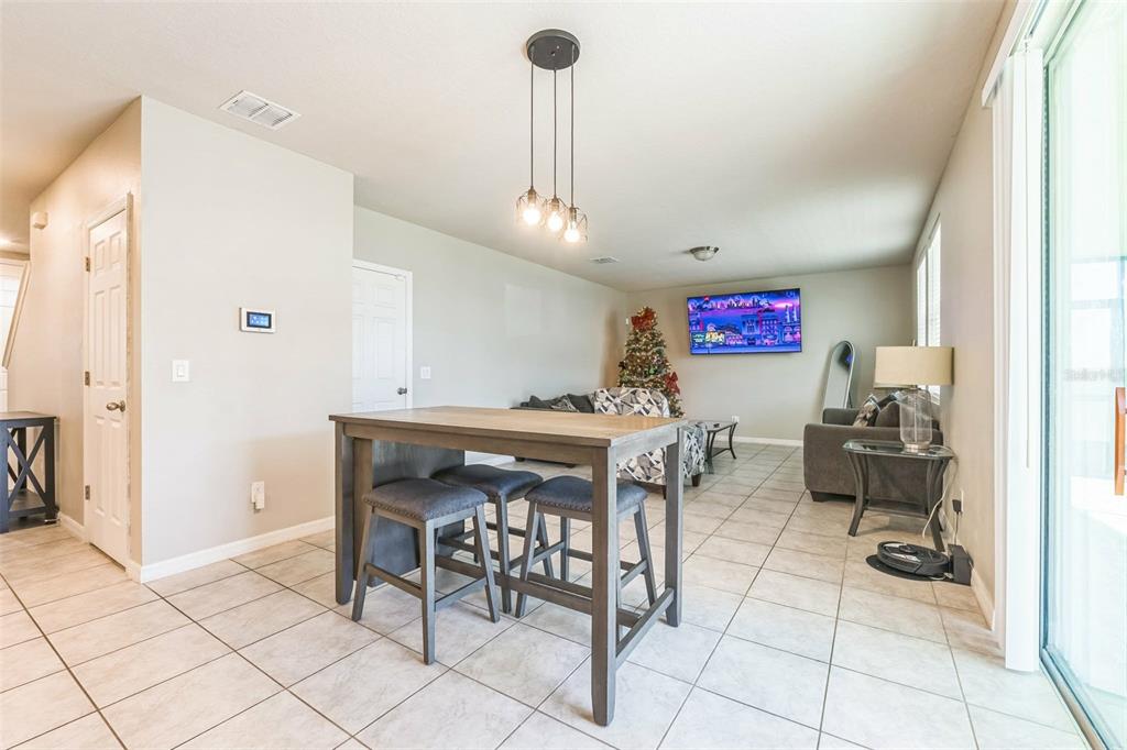 A living room and dining area feature tile flooring, a kitchen island, and a television — 1262 CITRUS LANDINGS BOULEVARD, DAVENPORT, FL