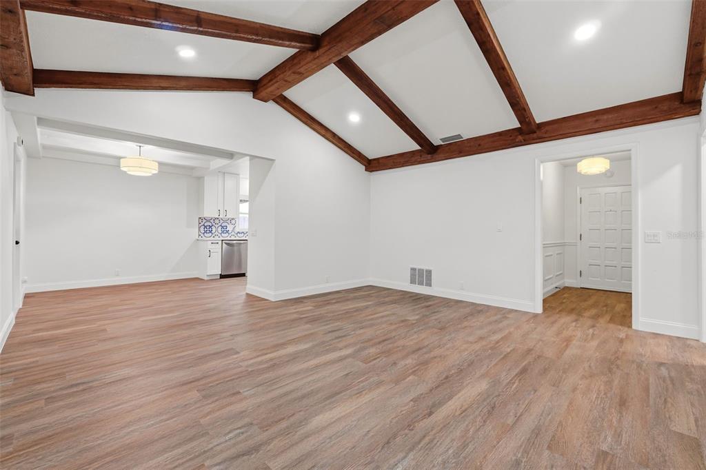 A living room with vaulted ceilings, exposed wooden beams, and light wood-look flooring — 205 WHITMAN ROAD, WINTER HAVEN, FL