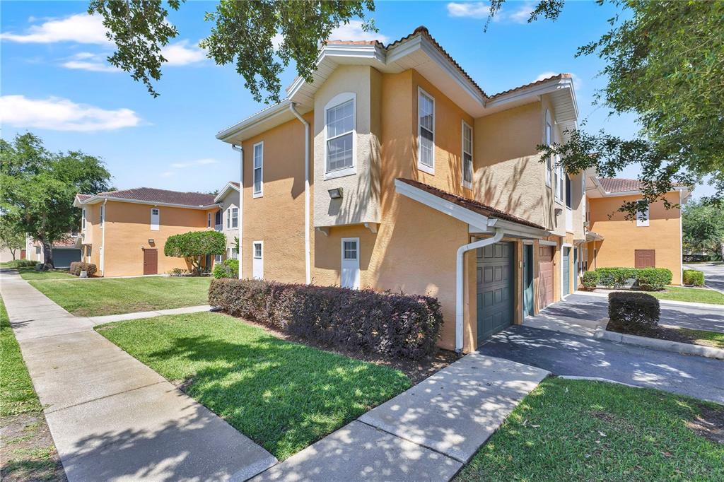 A two-story yellow stucco townhouse with a garage and a sidewalk in front — 12111 POPPY FIELD LANE UNIT 109, ORLANDO, FL