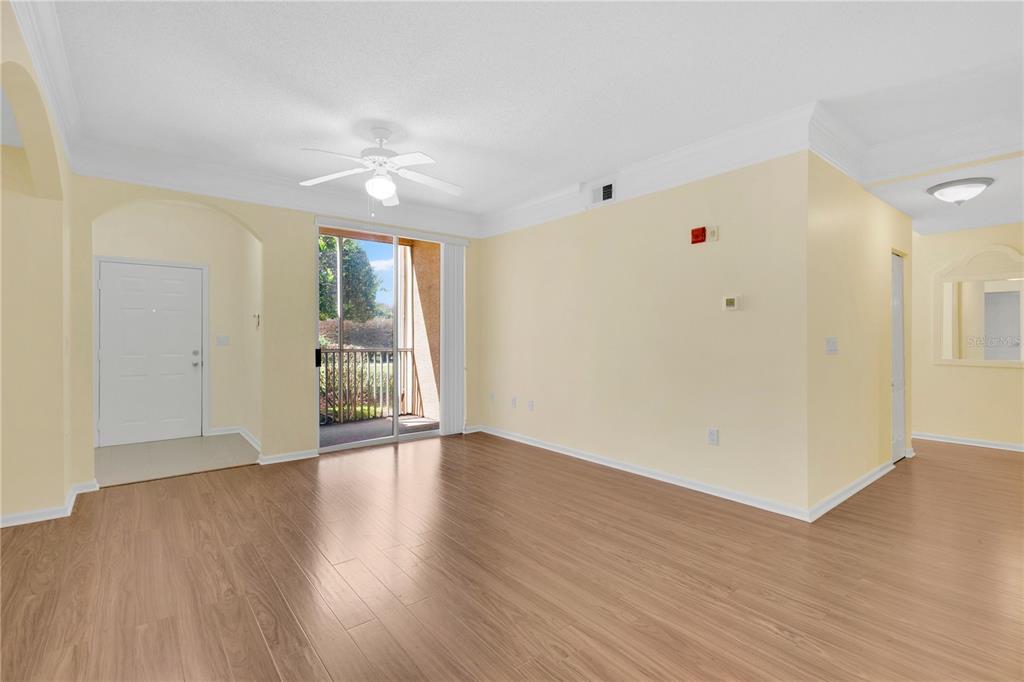 A living room with light yellow walls, wood-look flooring, a ceiling fan, and sliding doors — 12111 POPPY FIELD LANE UNIT 109, ORLANDO, FL
