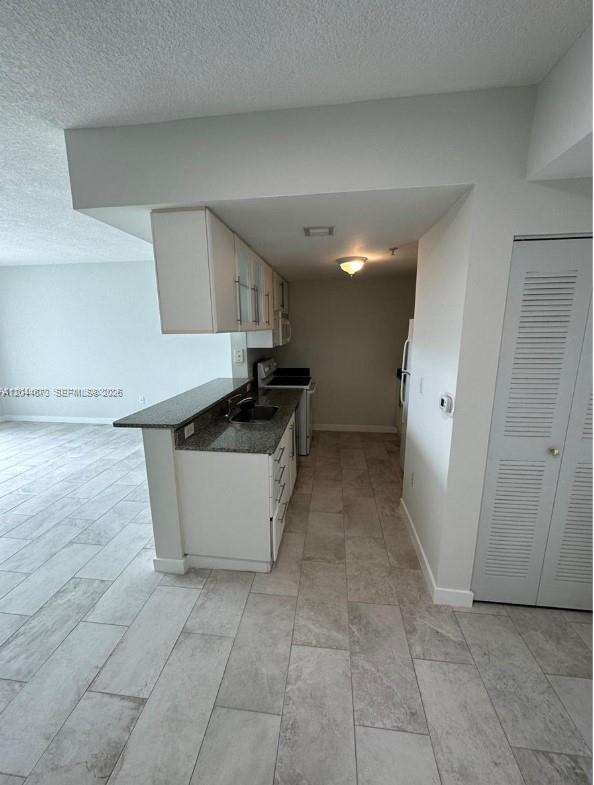 A kitchen with white cabinets, granite countertops, and light-colored tile flooring — 275 NE 18th St # 1406, Miami FL 33132, MIAMI, FL