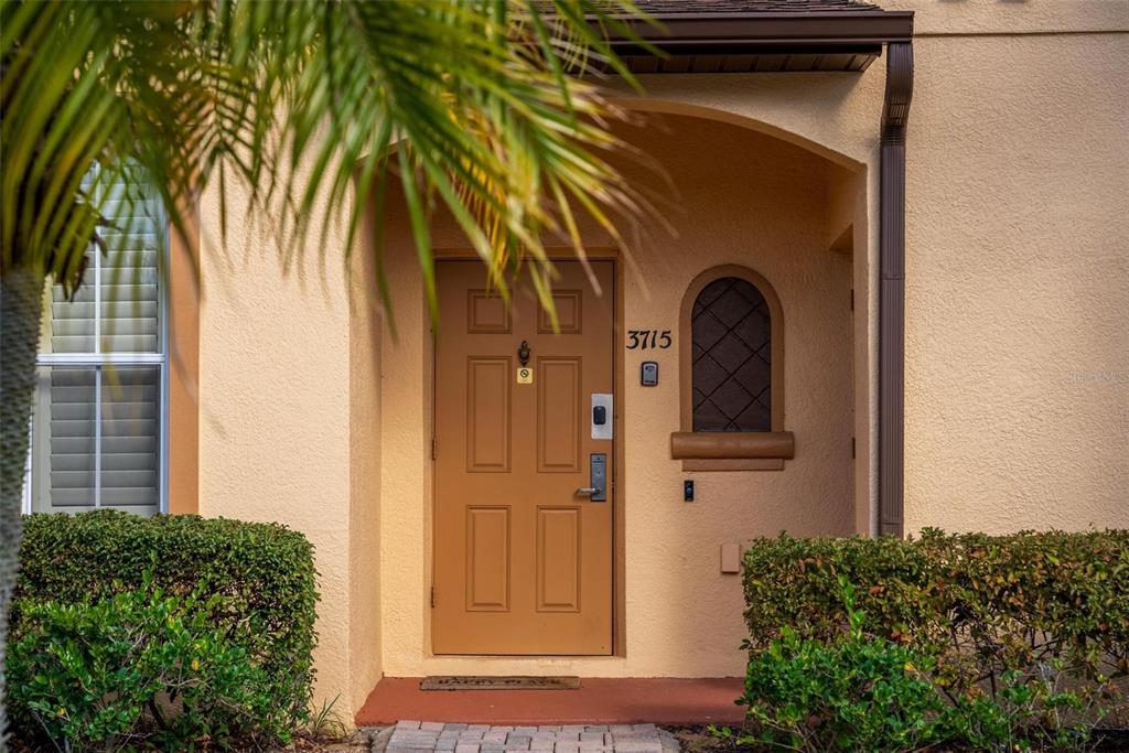 The exterior of a tan residential building features a brown front door with a window — 3715 CALABRIA AVENUE, DAVENPORT, FL