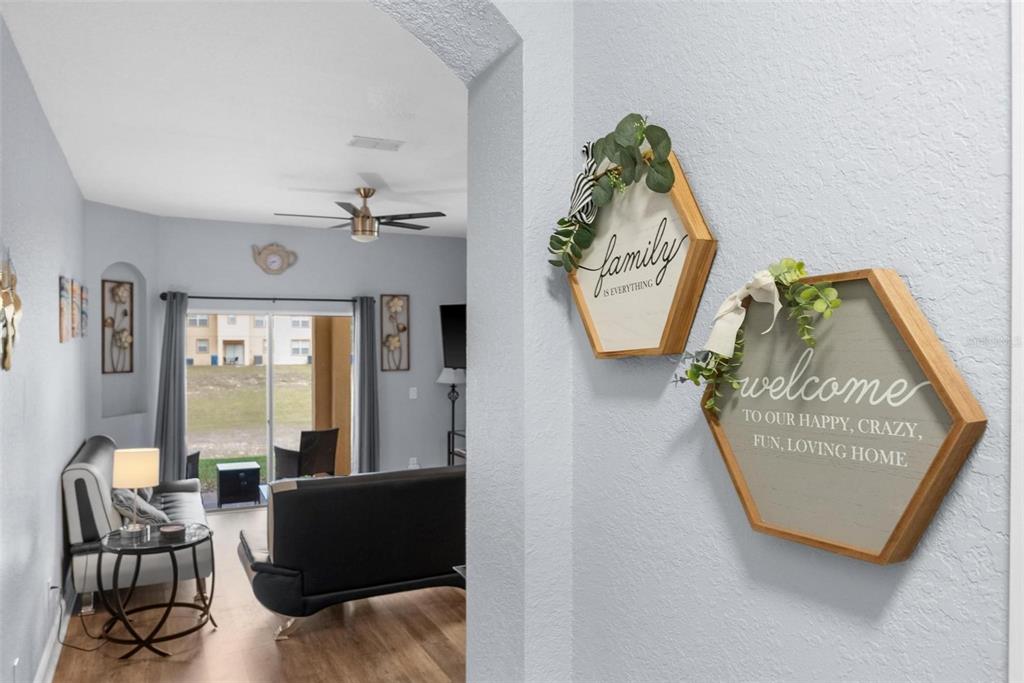 A view from a hallway into a living room with sliding glass doors and wall decor — 3715 CALABRIA AVENUE, DAVENPORT, FL