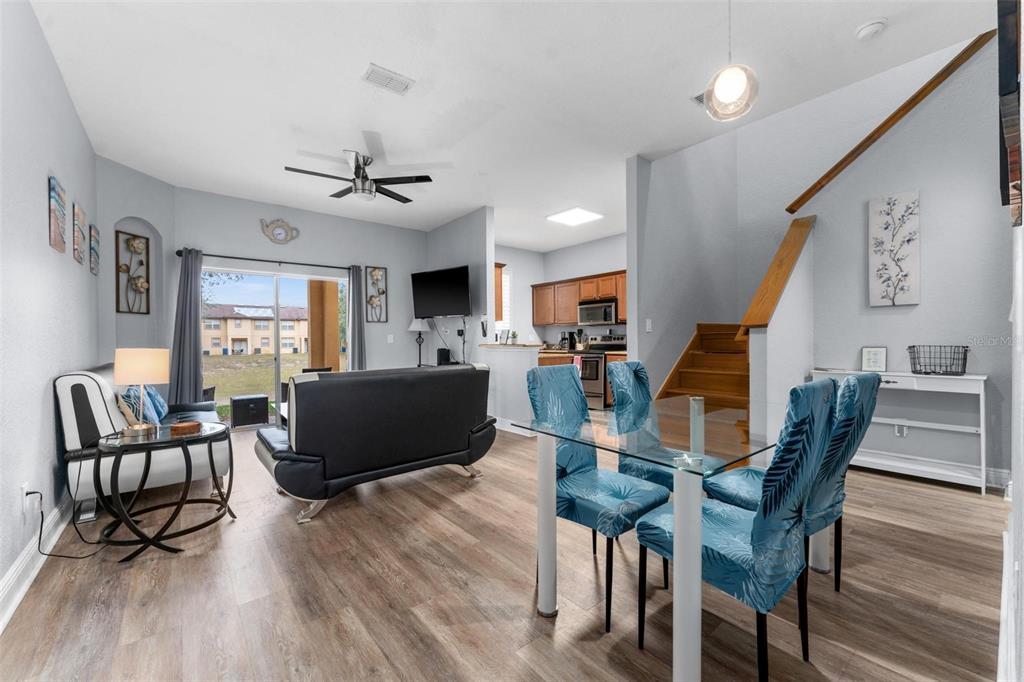An open-concept living and dining area features wood-look flooring, a kitchen, and a staircase — 3715 CALABRIA AVENUE, DAVENPORT, FL