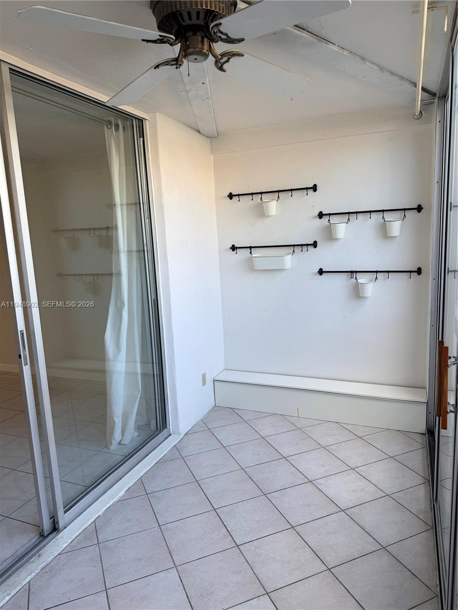 A tiled balcony features a ceiling fan, sliding glass doors, and wall-mounted storage racks — 501 E Dania Beach Blvd # 1B, Dania Beach FL 33004, DANIA BEACH, FL