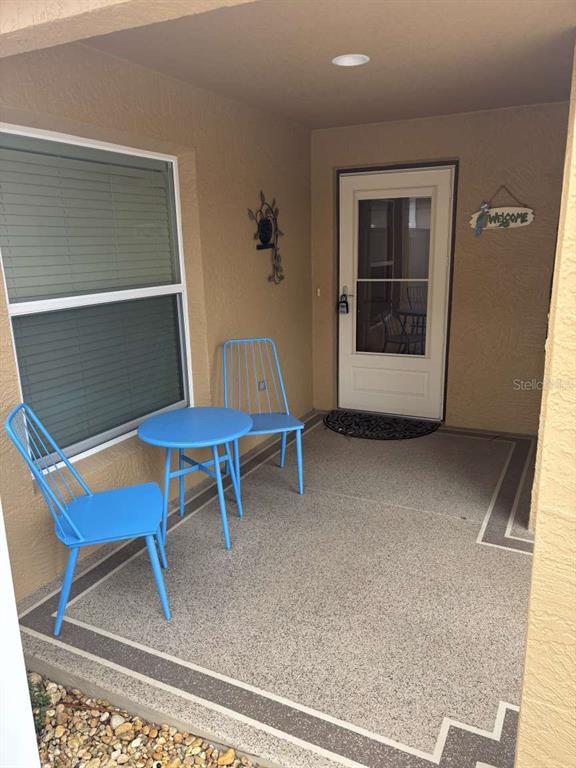 A covered patio features a small blue table with two matching chairs and a door — 1067 CARVER COURT, THE VILLAGES, FL