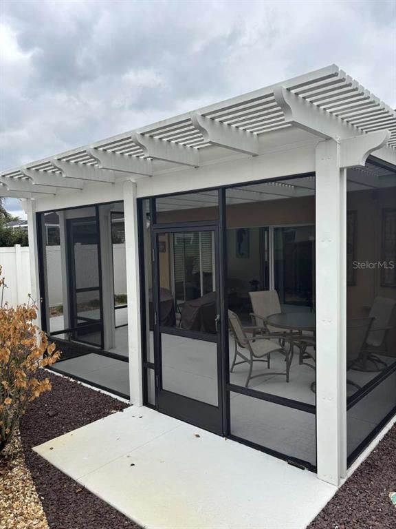 A screened-in patio features a white pergola roof, a screen door, and outdoor furniture — 1067 CARVER COURT, THE VILLAGES, FL