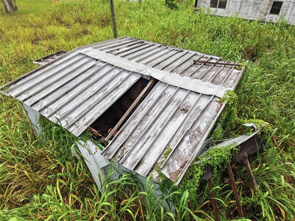 An aerial view of a small, dilapidated shed with a damaged metal roof in tall grass — 18052 2ND AVENUE, ORLANDO, FL