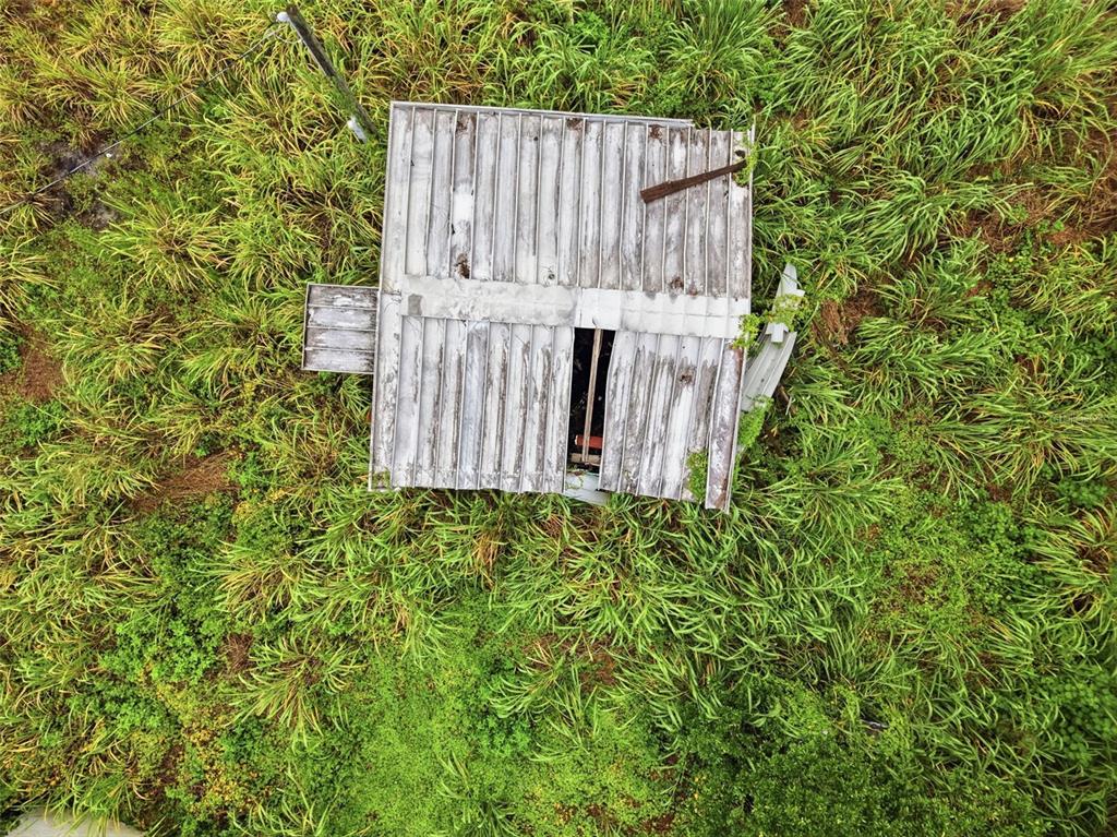 An aerial view shows a weathered, rectangular metal-roofed structure surrounded by dense green vegetation — 18052 2ND AVENUE, ORLANDO, FL