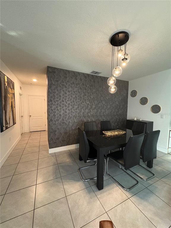 A dining room features a dark geometric accent wall, a black table, and modern pendant lighting — 336 GINA LANE, DAVENPORT, FL
