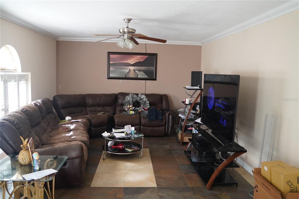 A living room features a brown sectional sofa, a glass coffee table, and a television stand — 304 COCOA COURT, KISSIMMEE, FL