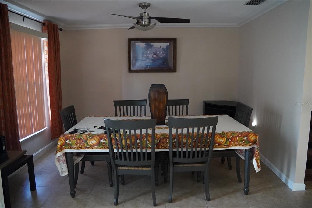 A dining room features a table with six chairs, a ceiling fan, and a wall painting — 304 COCOA COURT, KISSIMMEE, FL