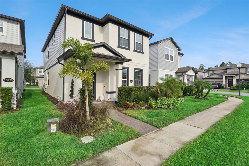 A two-story house with a stucco exterior, a palm tree, and a brick walkway — 13879 LANYARD WAY, WINTER GARDEN, FL