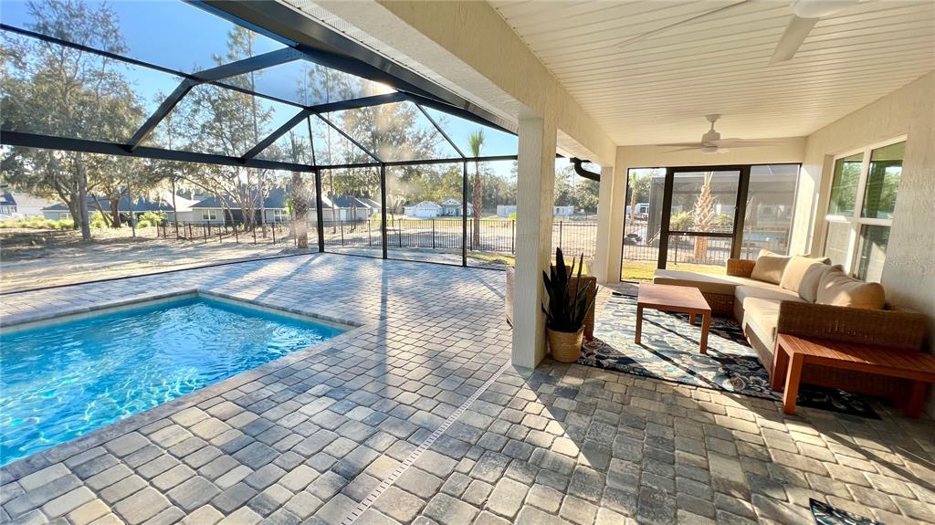 A covered patio with a pool, paver flooring, and outdoor furniture inside a screened enclosure — 17920 SW 66TH PLACE, DUNNELLON, FL