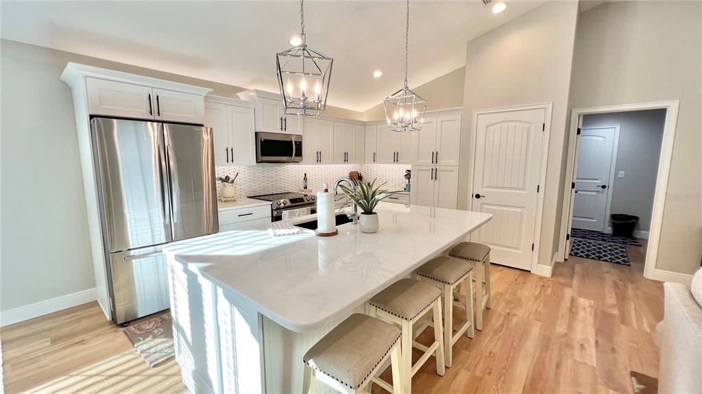 A modern kitchen features white cabinetry, stainless steel appliances, and a large quartz-topped island — 17920 SW 66TH PLACE, DUNNELLON, FL