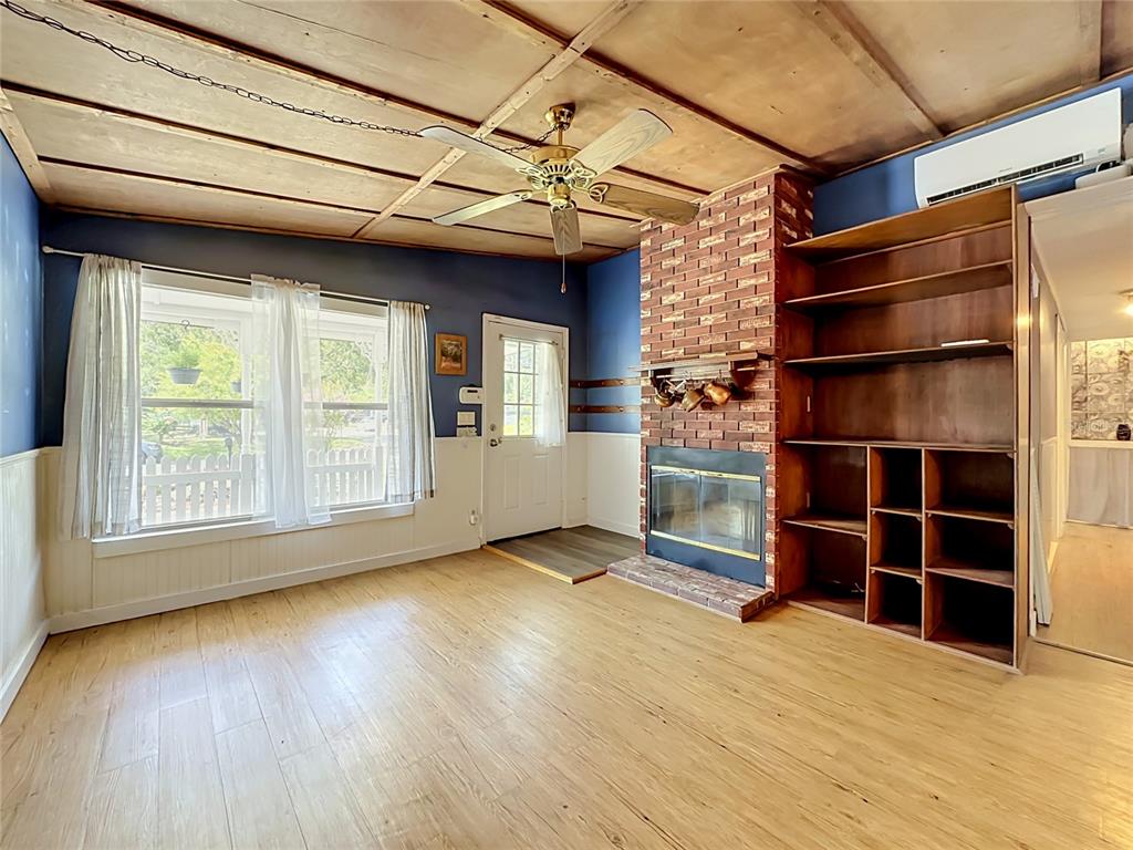 A living room features a brick fireplace, built-in shelving, a ceiling fan, and wood flooring — 10131 AGAVE ROAD, JACKSONVILLE, FL