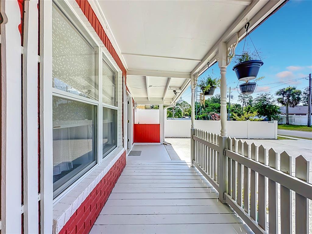 A covered porch features a red brick wall, white wooden railing, and hanging planters — 10131 AGAVE ROAD, JACKSONVILLE, FL