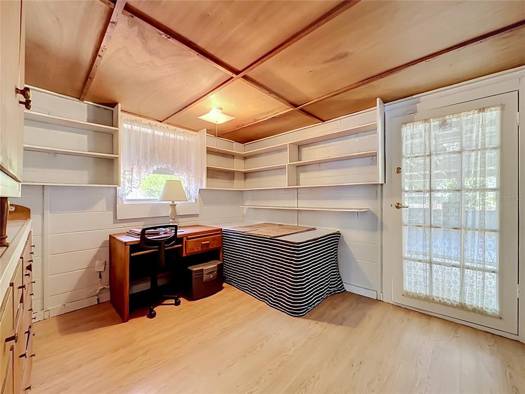 A home office features wood-paneled walls, built-in shelving, a desk, and a glass-paned door — 10131 AGAVE ROAD, JACKSONVILLE, FL