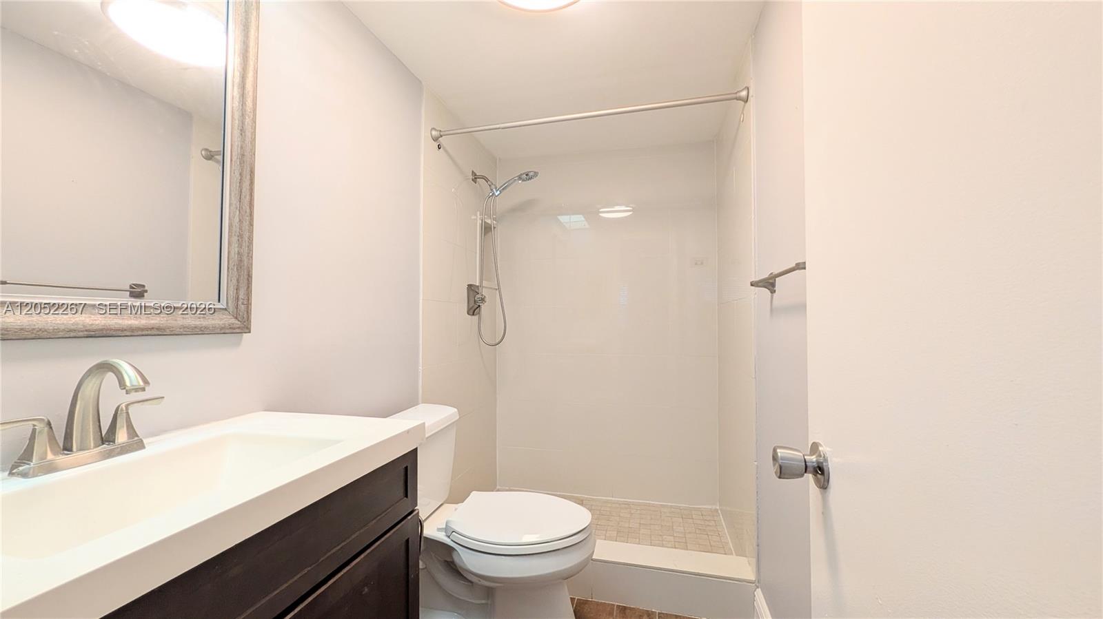 A bathroom features a dark wood vanity, a white toilet, and a tiled shower stall — 315 SE 23rd Ave # 5, Pompano Beach FL 33062, POMPANO BEACH, FL