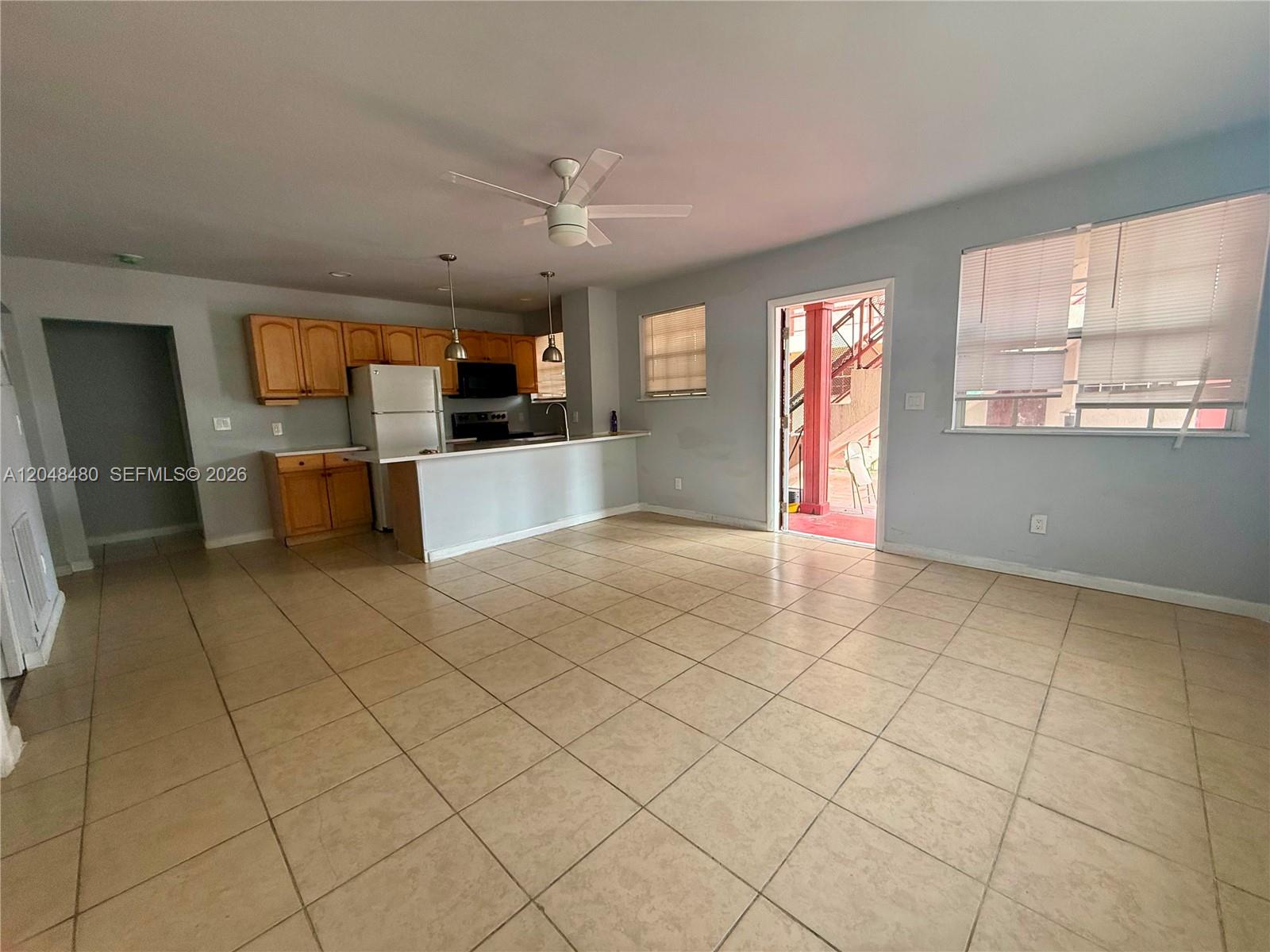 This open-concept kitchen and living area features light-colored tile flooring and wooden cabinetry — 14240 NW 22nd Ave # 1, Opa-Locka FL 33054, OPA-LOCKA, FL