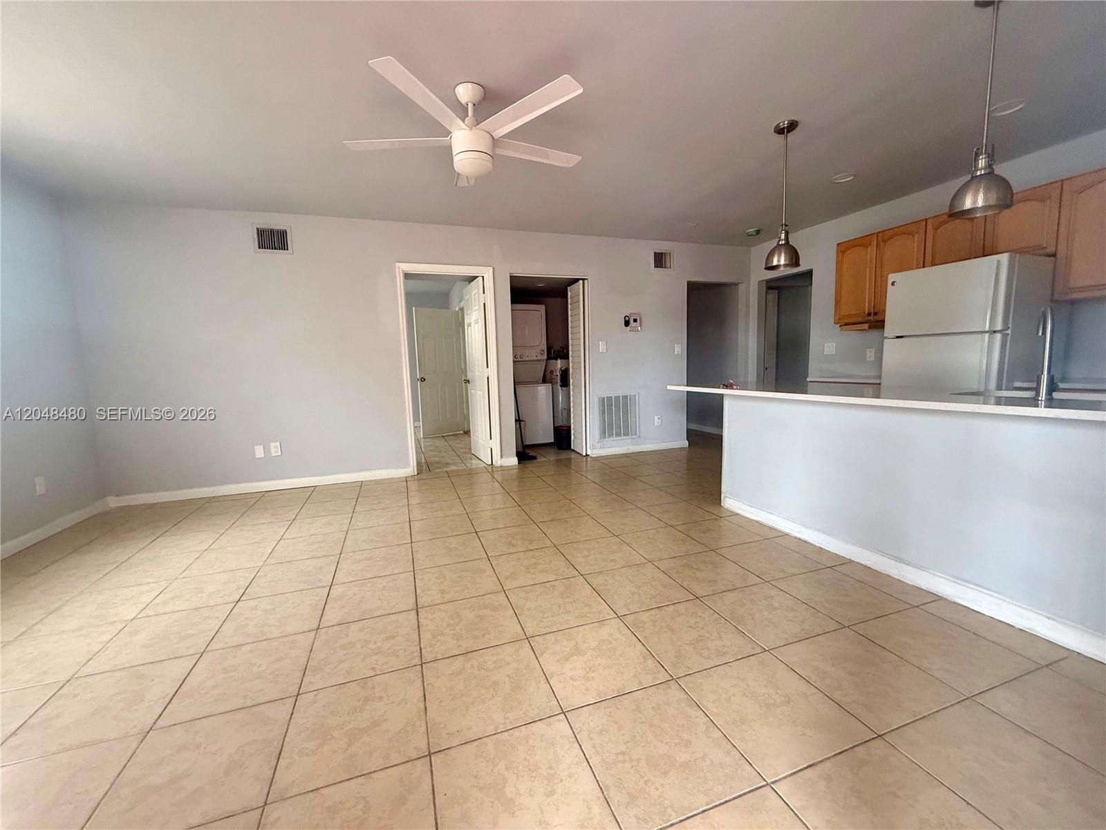 An open-concept living area features tile flooring, a ceiling fan, and an adjacent kitchen — 14240 NW 22nd Ave # 1, Opa-Locka FL 33054, OPA-LOCKA, FL