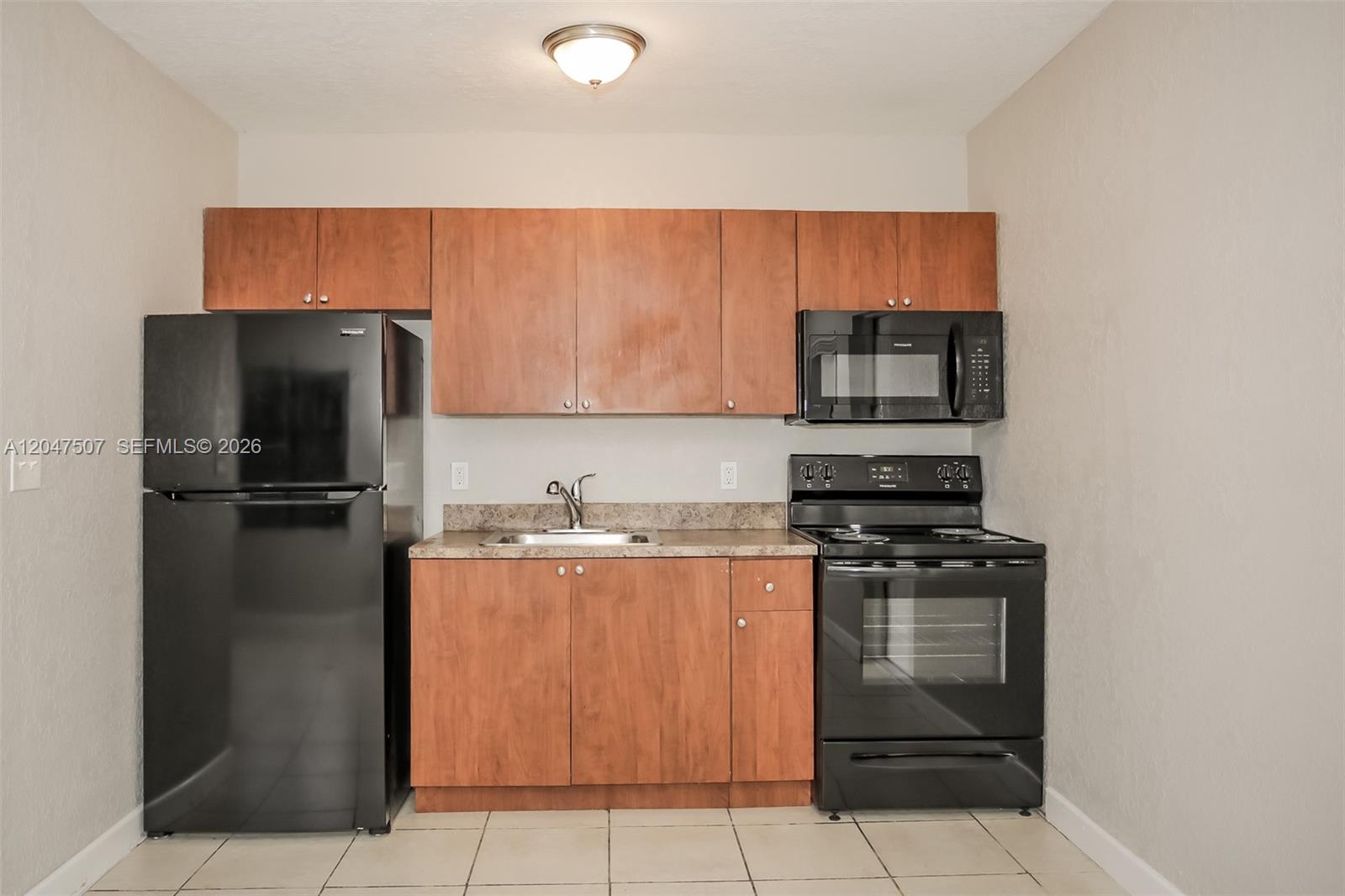 A small kitchen features wood cabinets, black appliances, and a stainless steel sink — 14640 Tyler St, Miami FL 33176, MIAMI, FL