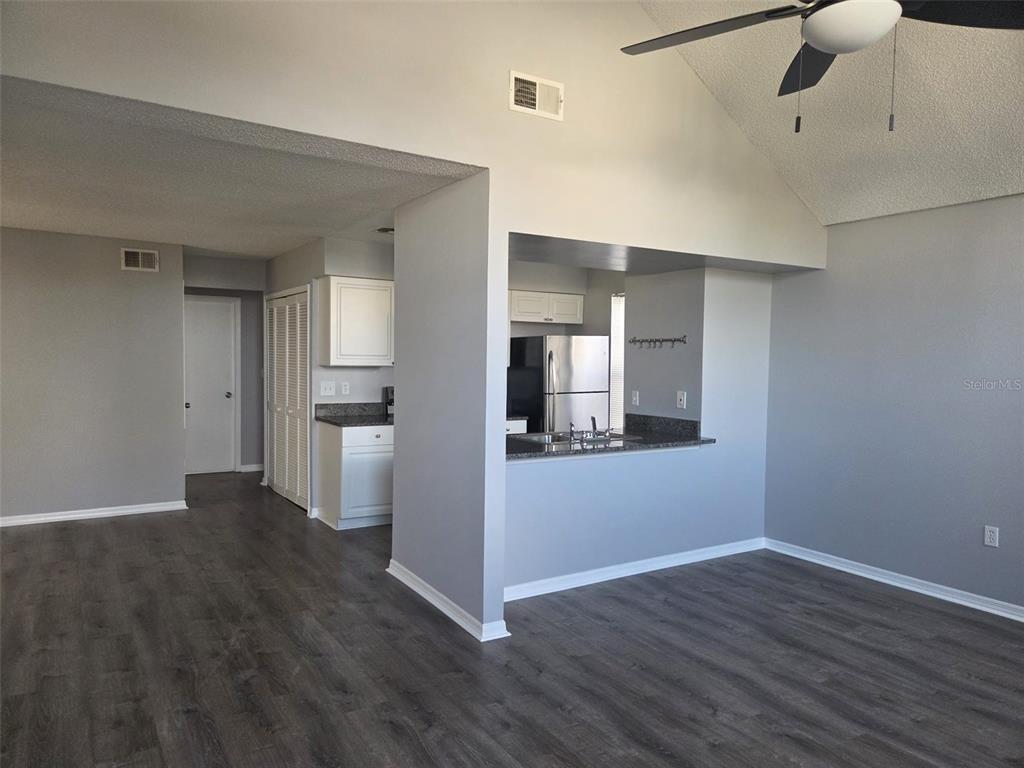 A kitchen with granite countertops and white cabinets overlooks a dining area with wood flooring — 3226 FOX SQUIRREL DRIVE, KISSIMMEE, FL