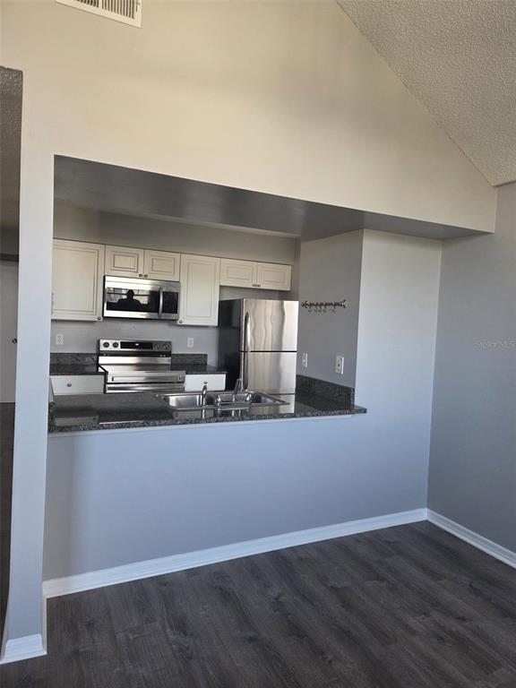 A kitchen with stainless steel appliances, white cabinets, and granite countertops overlooks a dining area — 3226 FOX SQUIRREL DRIVE, KISSIMMEE, FL