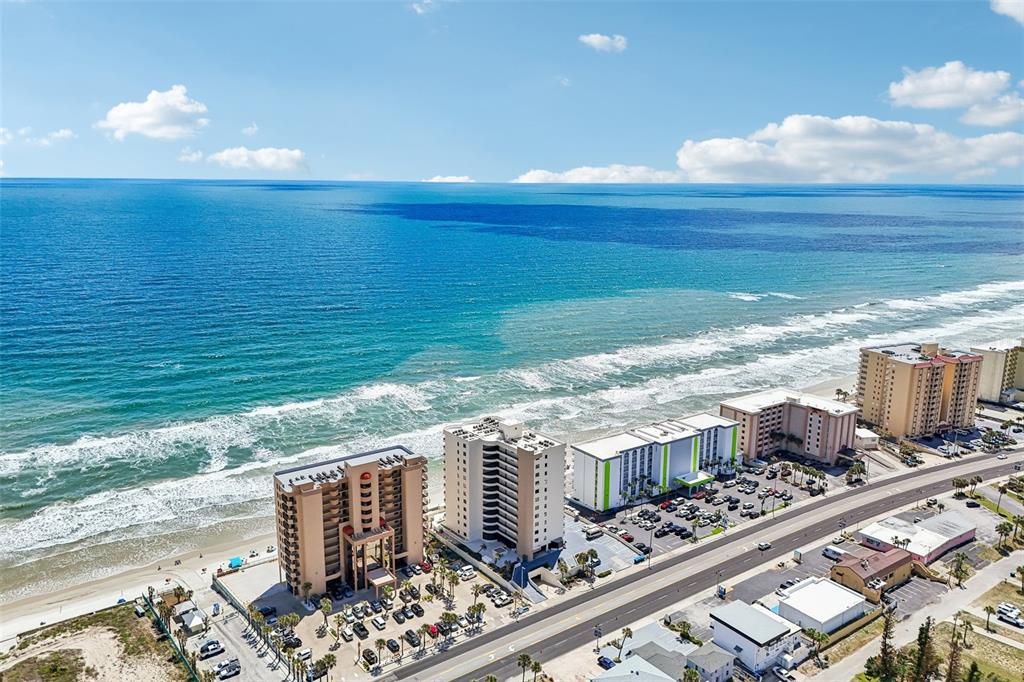 An aerial view shows several beachfront high-rise hotels along a coastline with a road nearby — 3115 S ATLANTIC AVENUE UNIT G030, DAYTONA BEACH, FL