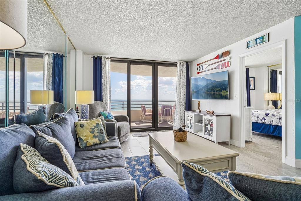 A living room features a blue sofa, a coffee table, and a balcony overlooking the ocean — 3115 S ATLANTIC AVENUE UNIT G030, DAYTONA BEACH, FL